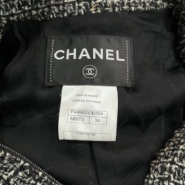 Veste T34 CHANEL en tweed noir et blanc avec fil doré. Fermeture avec zip et deux poches passepoilées sur le devant